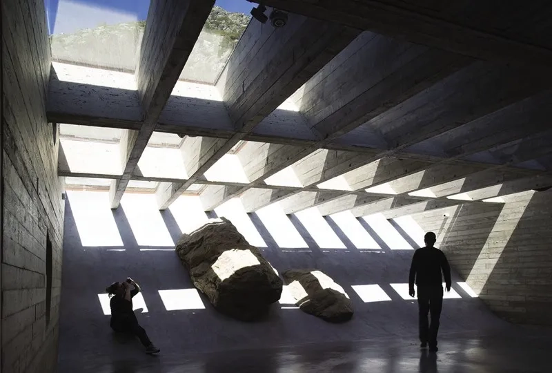 Les poutres croisées en béton portent la verrière. À travers la résille de la structure, des vues cadrées en contre- plongée sur le mont Gerbier- de-Jonc sont proposées aux visiteurs.