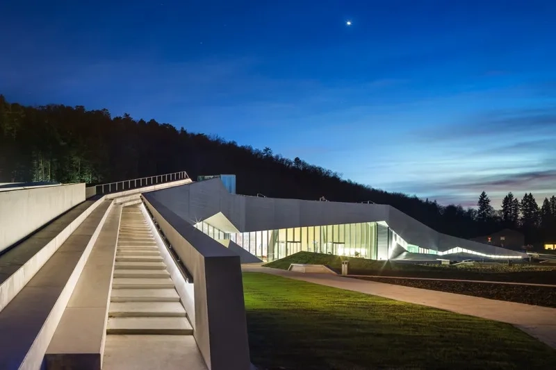 De nuit, la lumière souligne les découpes du béton.