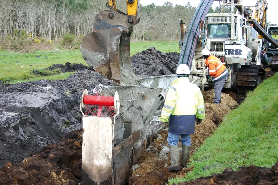 disposés en trèfle au fond de la tranchée, les câbles sont recouverts de remblai liquide, puis la tranchée est comblée avec la terre excavée. Un grillage de plastique rouge inséré dans la tranchée signale la présence de la ligne haute tension.