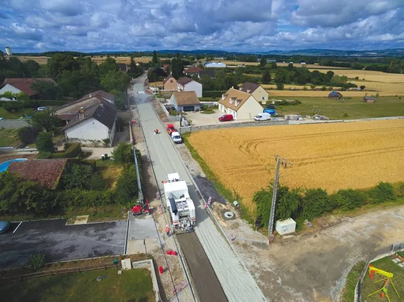 Fin juin 2017, à Demigny (Saône- et-Loire). Après épandage du liant hydraulique routier Vicat (LV-TS03) par l'Arc Dosage (en haut de la photo), l’Arc 1000 (au premier plan) décohésionne les matériaux de l’ancienne chaussée et procède à un puissant malaxage pour obtenir un mélange homogène.