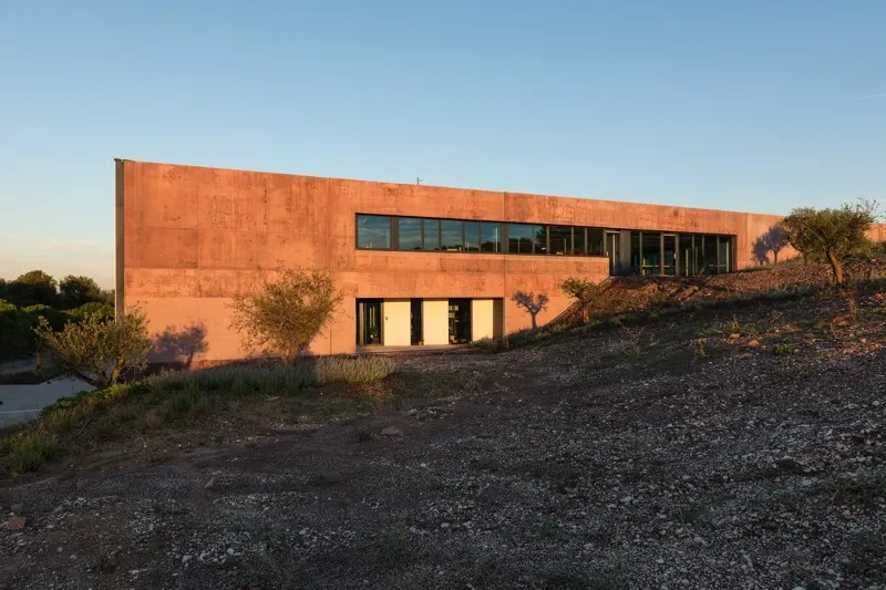 Les pignons ont été travaillés pour donner une impression de masse. Le béton reprend les teintes rouges de la colline.