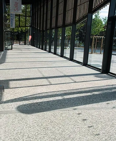  La coursive en béton bouchardé prolonge le parvis à l’intérieur du bâtiment.