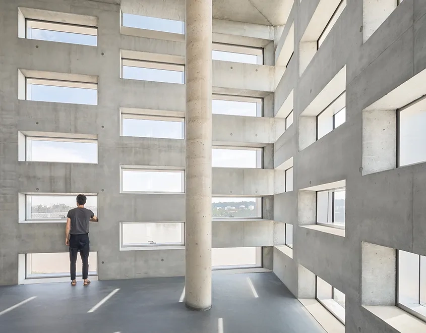 Dans les espaces du bureau, les matériaux sont laissés bruts. L’épaisseur des façades de béton laisse pénétrer la lumière tout en faisant brise-soleil. 