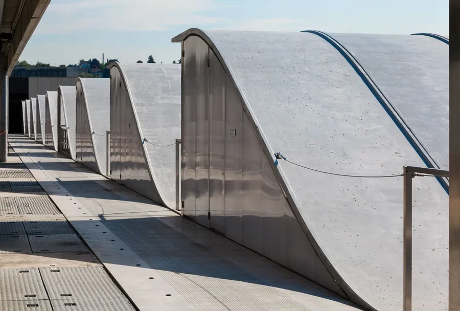 L’unité de post- dénitrification des eaux est desservie par une grande faille organisée entre les bassins de traitement et les locaux techniques intégrés sous une terrasse- jardin. une création originale de coques structurelles précontraintes et de  nes résilles à base de BFUP se développe en couverture et en façade des bassins de traitement.